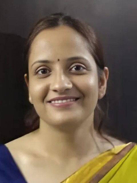 Dr. Reetika Sharma in a yellow saree, smiling