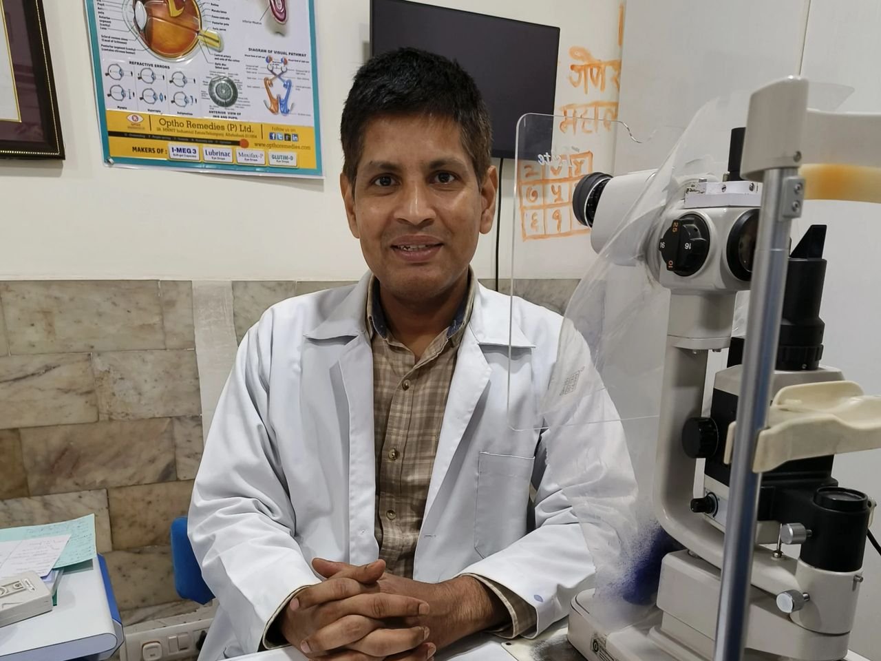Dr. Gautam, one of our directors, at his desk beside a slit lamp